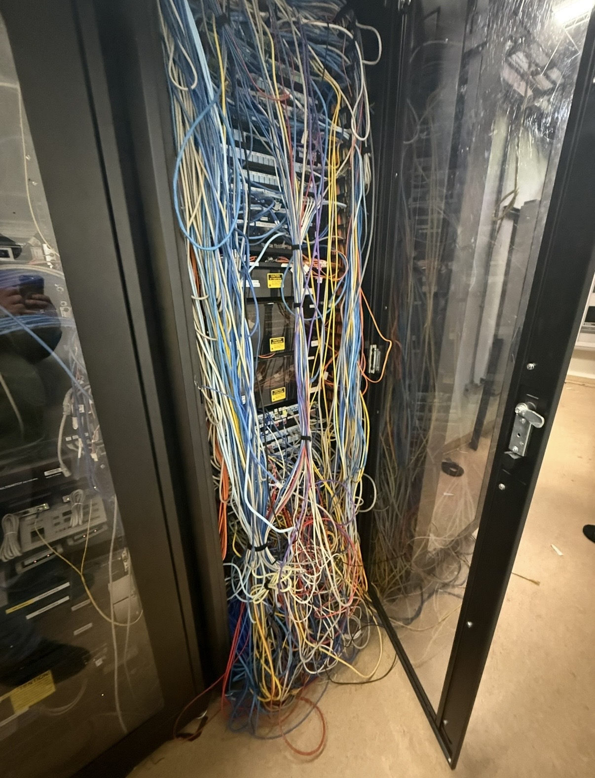 Network cabinet with loose and tangled cables before cable management cleanup