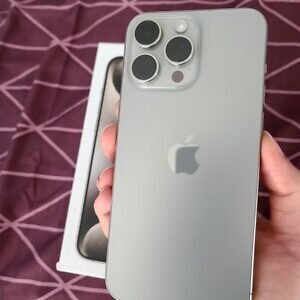 iPhone 15 Pro Max in natural titanium held in hand, with its original box