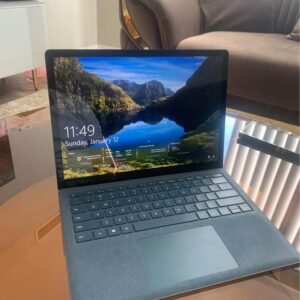 Microsoft Surface Laptop 3 open on a glass table showing the lock screen