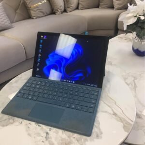 Microsoft Surface Pro 6 with blue keyboard cover on a marble table, Windows 11 on screen