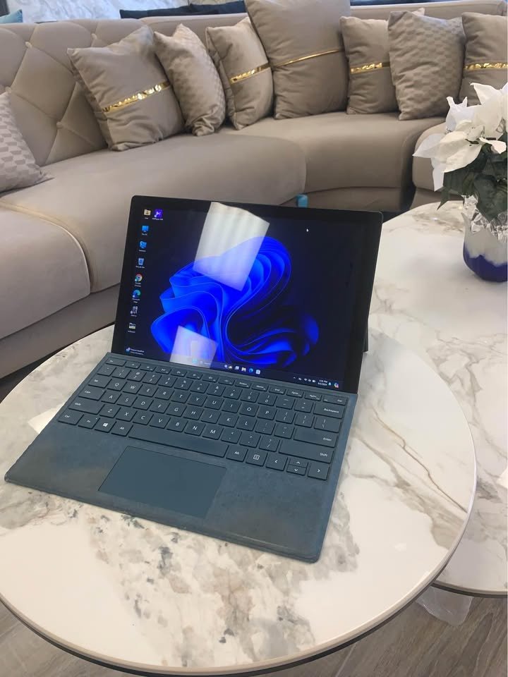 Microsoft Surface Pro 6 with blue keyboard cover on a marble table, Windows 11 on screen